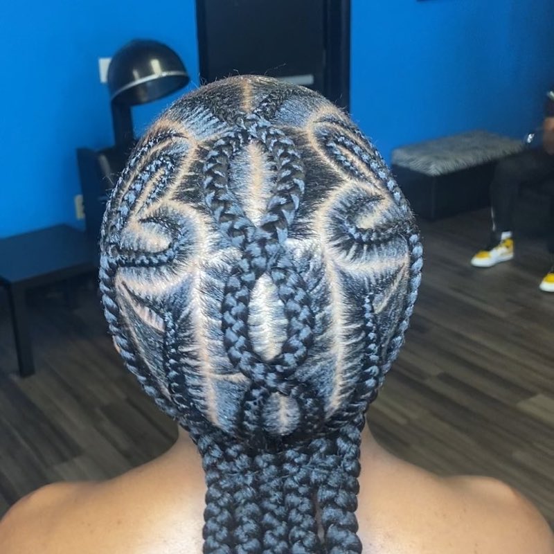 Cornrow braids with a detailed design against a blue wall