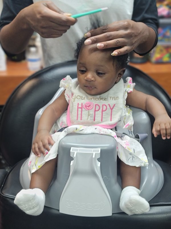 A baby girl getting her hair done in the salon chair